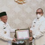 GUBERNUR Malut Abdul Gani Kasuba (kiri) menyerahkan penghargaan kepada Penjabat Bupati Kepulauan Sula Idham Umasangadji (kanan)